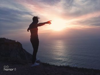 Silhouette woman standing on beach against sky during sunset