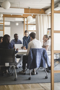 Male and female coworkers brainstorming in meeting at creative office