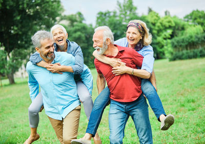 Happy friends sitting on group of people against blurred background