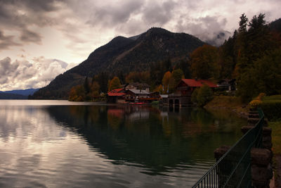 Scenic view of lake by houses and mountains against sky