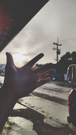 Close-up of hand holding cable car against sky