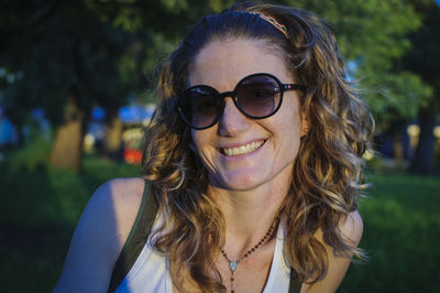 Portrait of young woman wearing sunglasses against trees