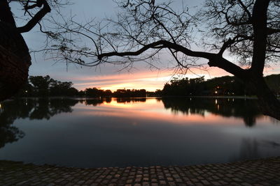 Reflection of trees in calm lake at sunset