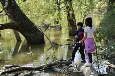 Full length of kids on lake amidst trees
