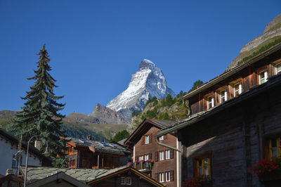 Houses by snowcapped mountains against clear sky