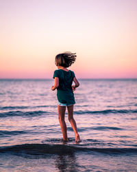 Full length of boy standing on beach against sky during sunset