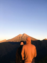 Rear view of man standing with woman against sky