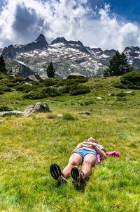 Woman lying down on field against mountains