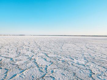 Scenic view of frozen lake against clear blue sky