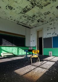 Stack of books on table with chair in abandoned classroom