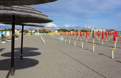 Row of chairs on beach against sky