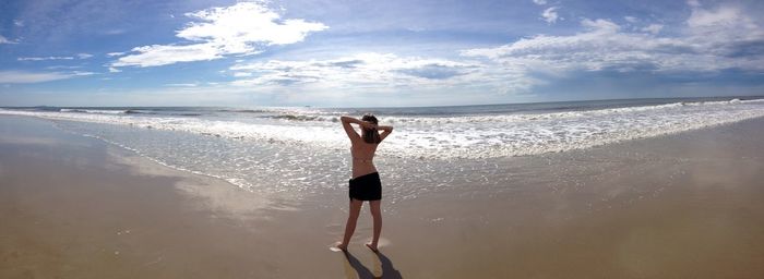 Rear view of woman standing on shore at beach