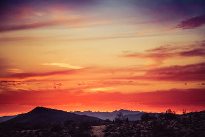 Scenic view of silhouette mountains against orange sky