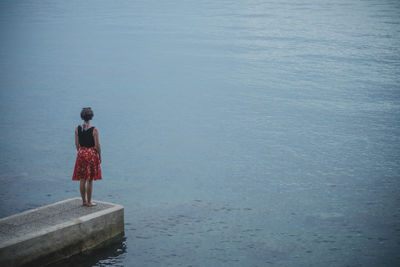 Woman standing on jetty by sea