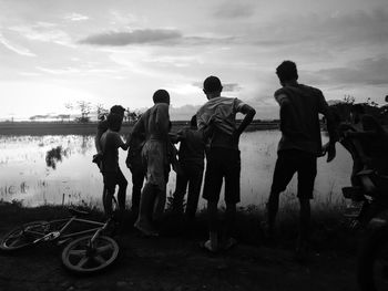 Men standing on riverbank against sky