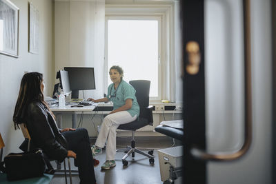 Female physician discussing with young woman in clinic