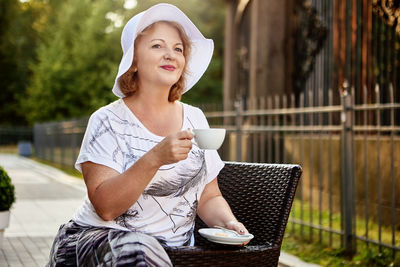 Young woman drinking coffee while sitting outdoors