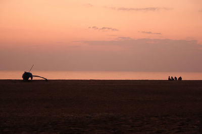 Silhouette man standing on shore against sky during sunset