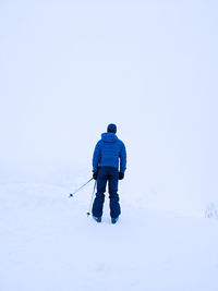 Rear view of man in snow against sky