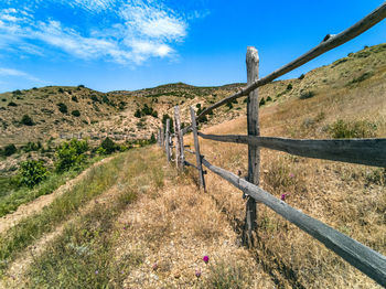 Fence on field against blue sky