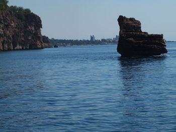 Rock formation in sea against clear sky