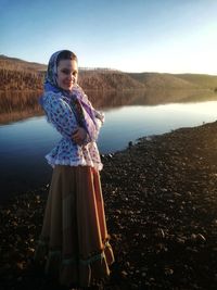 Portrait of woman standing by lake against sky