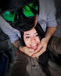 High angle portrait of happy woman with boyfriend sitting outdoors