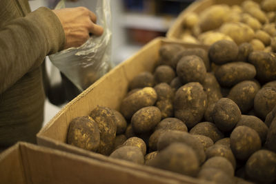 Man takes potatoes at market. guy puts root vegetable in bag. potatoes on market. plastic food bag.