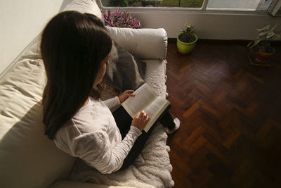 High angle view of woman sitting on sofa at home