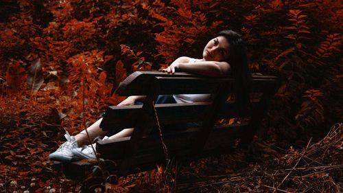 Young woman sitting on land in autumn