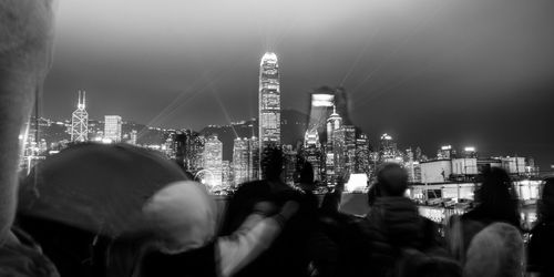 Crowd on illuminated city against sky at night