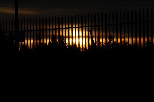 sunset, sun, silhouette, fence, orange color, sunlight, tranquility, water, sea, reflection, tranquil scene, scenics, beauty in nature, nature, safety, protection, idyllic, sky, dark, no people