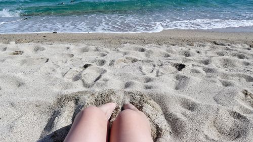 Low section of person legs on sand at beach