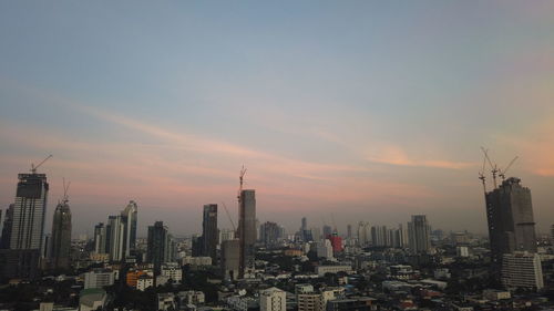 Modern buildings in city against sky during sunset