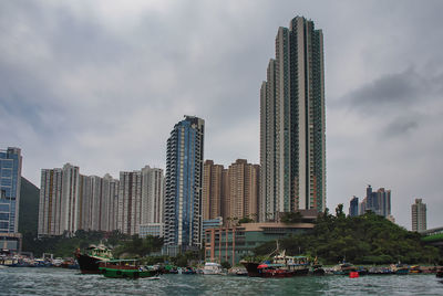 Sailboats in city by buildings against sky