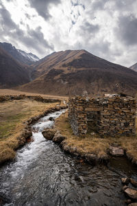 Scenic view of river by mountains against sky