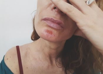 Midsection of mature woman with head in hand against wall