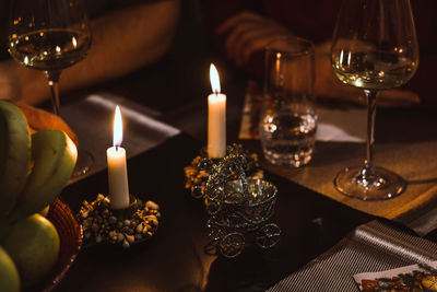 Candles and wineglasses by fruits on table