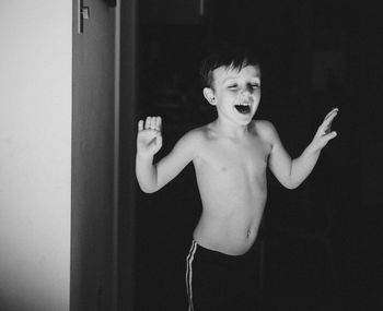 Cheerful shirtless boy standing at doorway