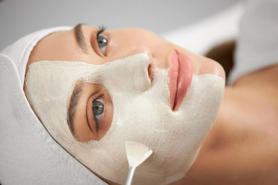 Close-up portrait of woman applying facial mask at spa