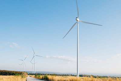 Windmills on field against clear sky