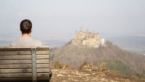 Person looking at hohenzollern castle sitting on top of a hilltop in baden-württemberg, germany.