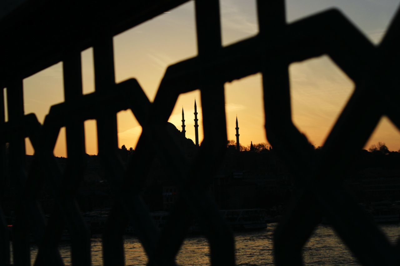 silhouette, sunset, shadow, sunlight, railing, unrecognizable person, built structure, lifestyles, indoors, men, architecture, leisure activity, sky, outline, orange color, fence, focus on shadow