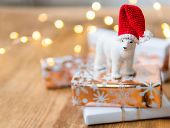Christmas presents on shabby wooden table. cute polar bear in santa hat standing on new year gifts.