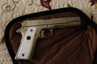 Close-up of handgun on bed