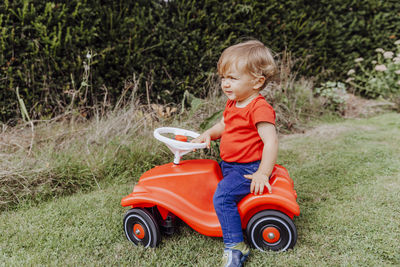 Side view of a boy sitting on toy car