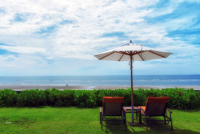 Deck chairs on beach against sky