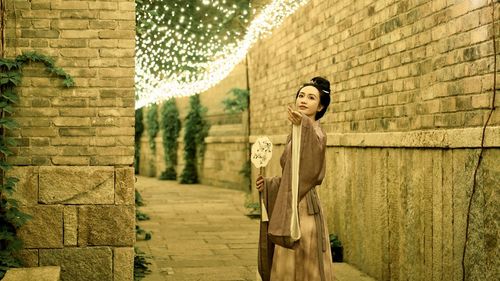 Rear view of woman standing against wall
