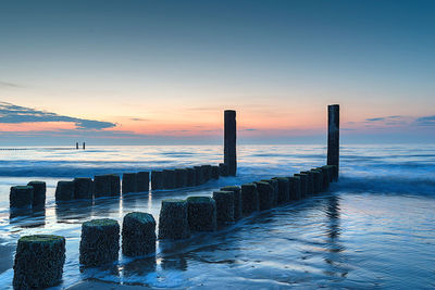 Wooden poles in the sand against the evening sun