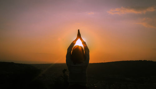 Rear view of man standing against sky during sunset